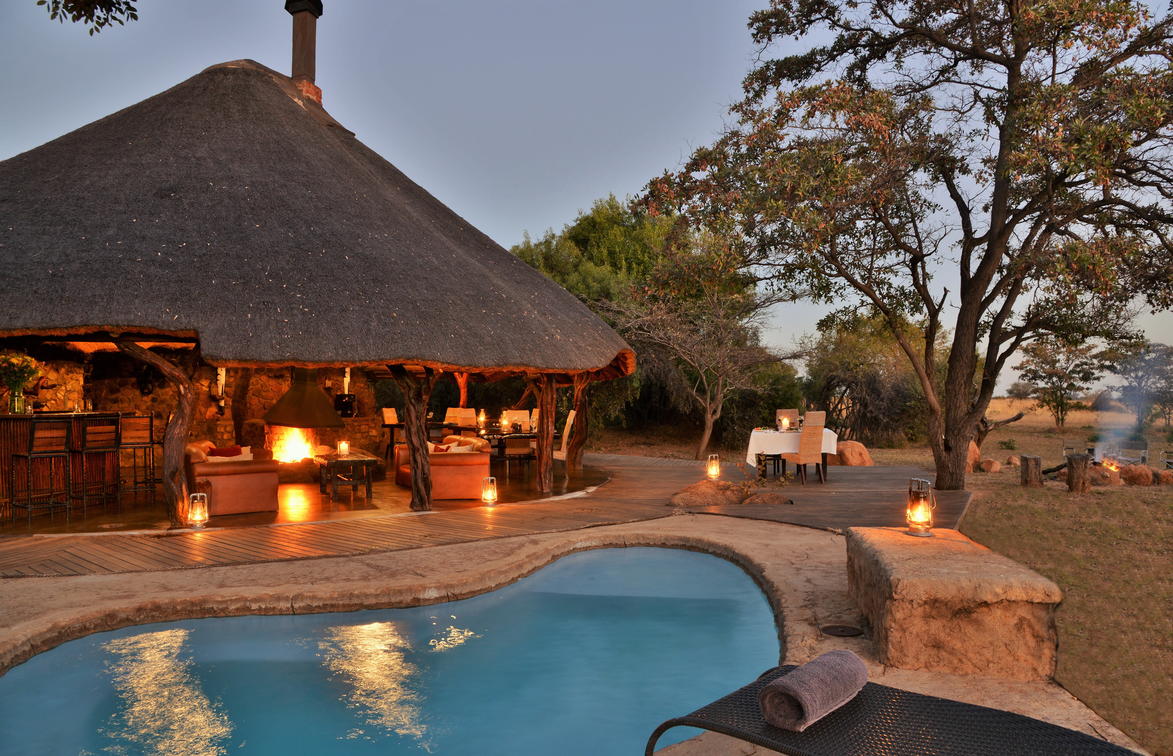 Rieten huisje met zwembad en sfeerlampen op safari in Zuid-Afrika