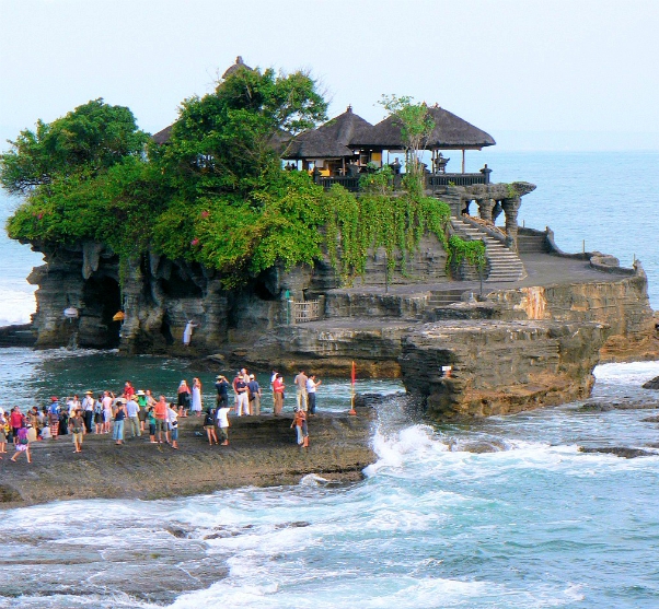 Mensen staan bij de hindoetempel Pura Tanah Lot, gebouwd op een rots in de zee in Bali