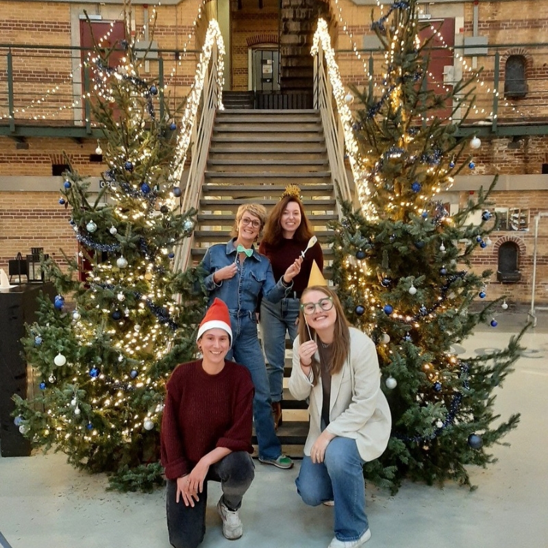 Werknemers poseren tussen kerstbomen en dragen kerstversiering