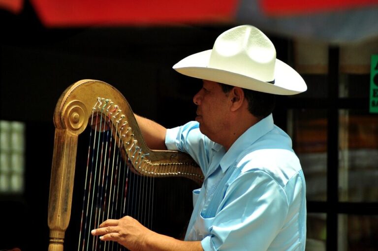 Mexicaanse man met witte hoed op en een gouden harp in de handen