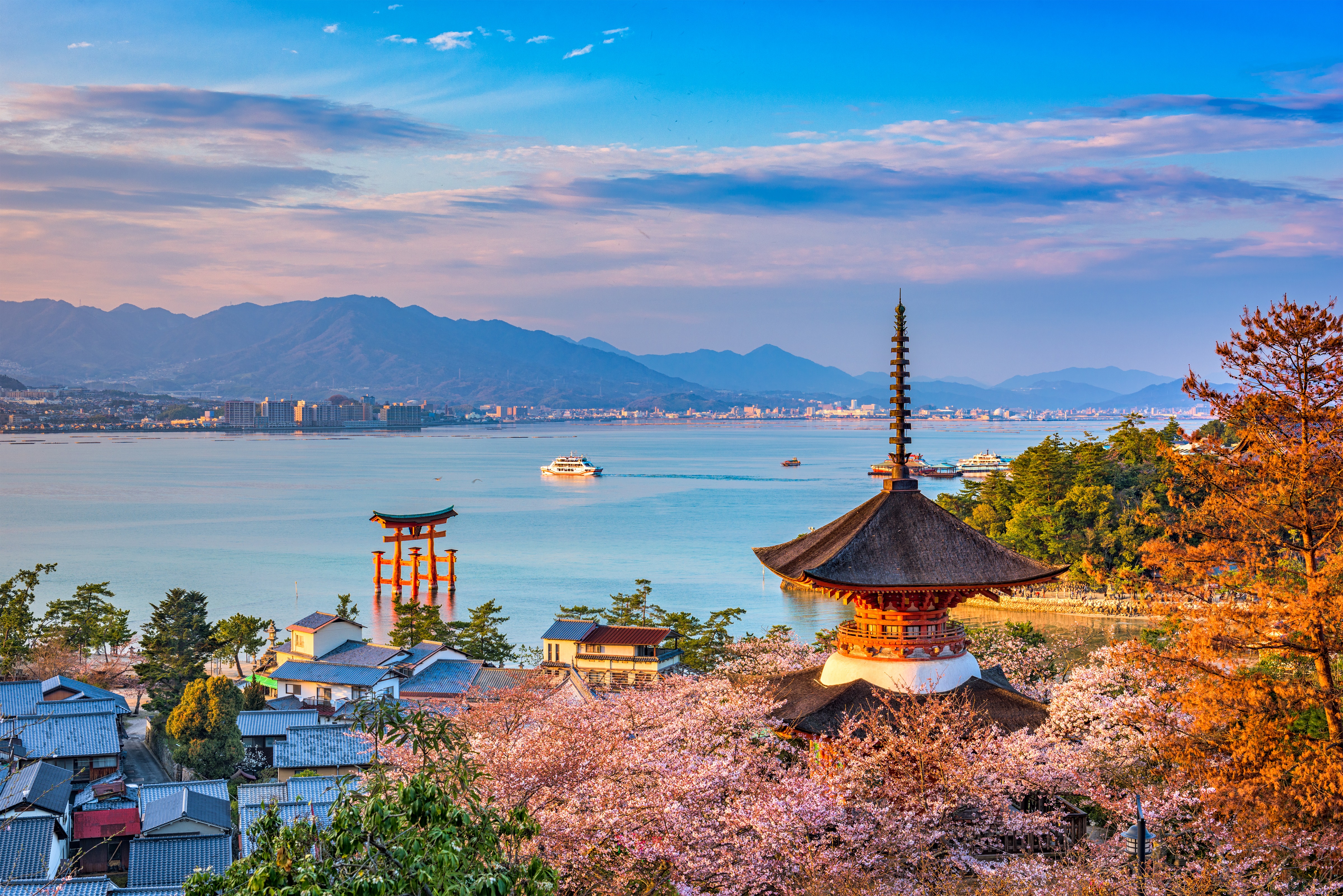 Miyajima-eiland met de rode pagode en grote torii-poort in het water omringd door kersenbloesem