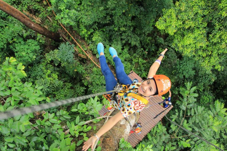 een toerist hangt hoog bovenin de boomtoppen aan een zipline