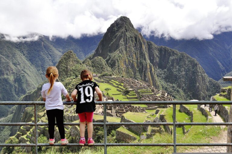 twee kinderen op een hek kijkend naar de ruïnes van machu picchu