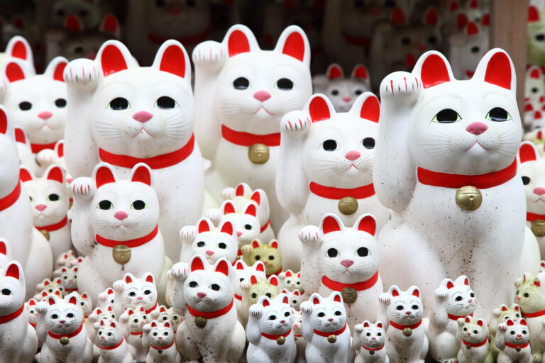 Tientallen aneki-neko zwaaiende katten beeldjes, die traditioneel geluk en voorspoed symboliseren