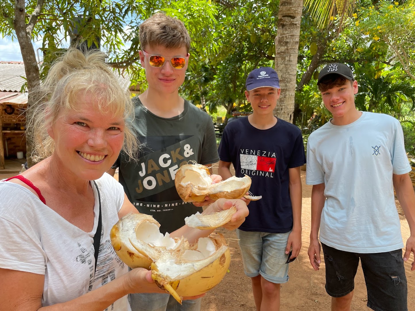 Gezin met drie jongens die samen met moeder een kokosnoot proberen in Sri Lanka