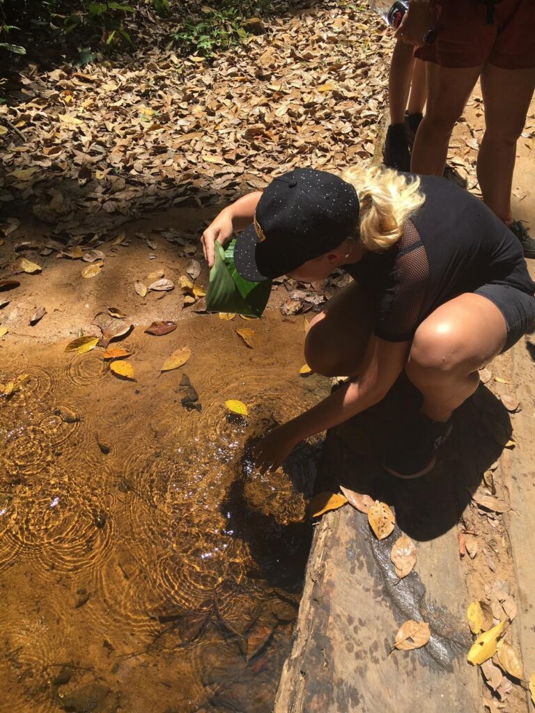 vrouw zit gehurkt bij riviertje in Suriname