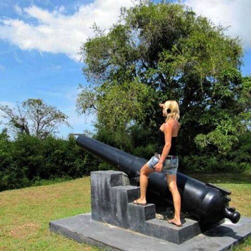 vrouw staat bij kanon van openluchtmuseum van Fort Nieuw-Amsterdam in Suriname
