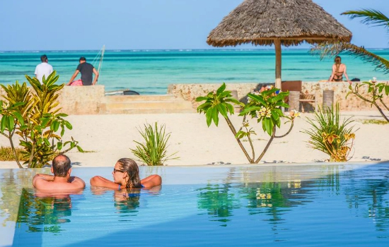 Reizigers in het zwembad kijkend op de zee bij Nur Beach Tanzania