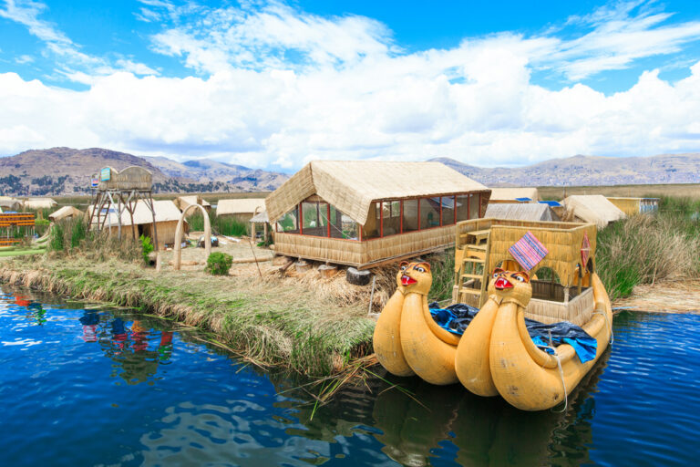 bootjes op het titicaca meer met rieten huisjes op het land