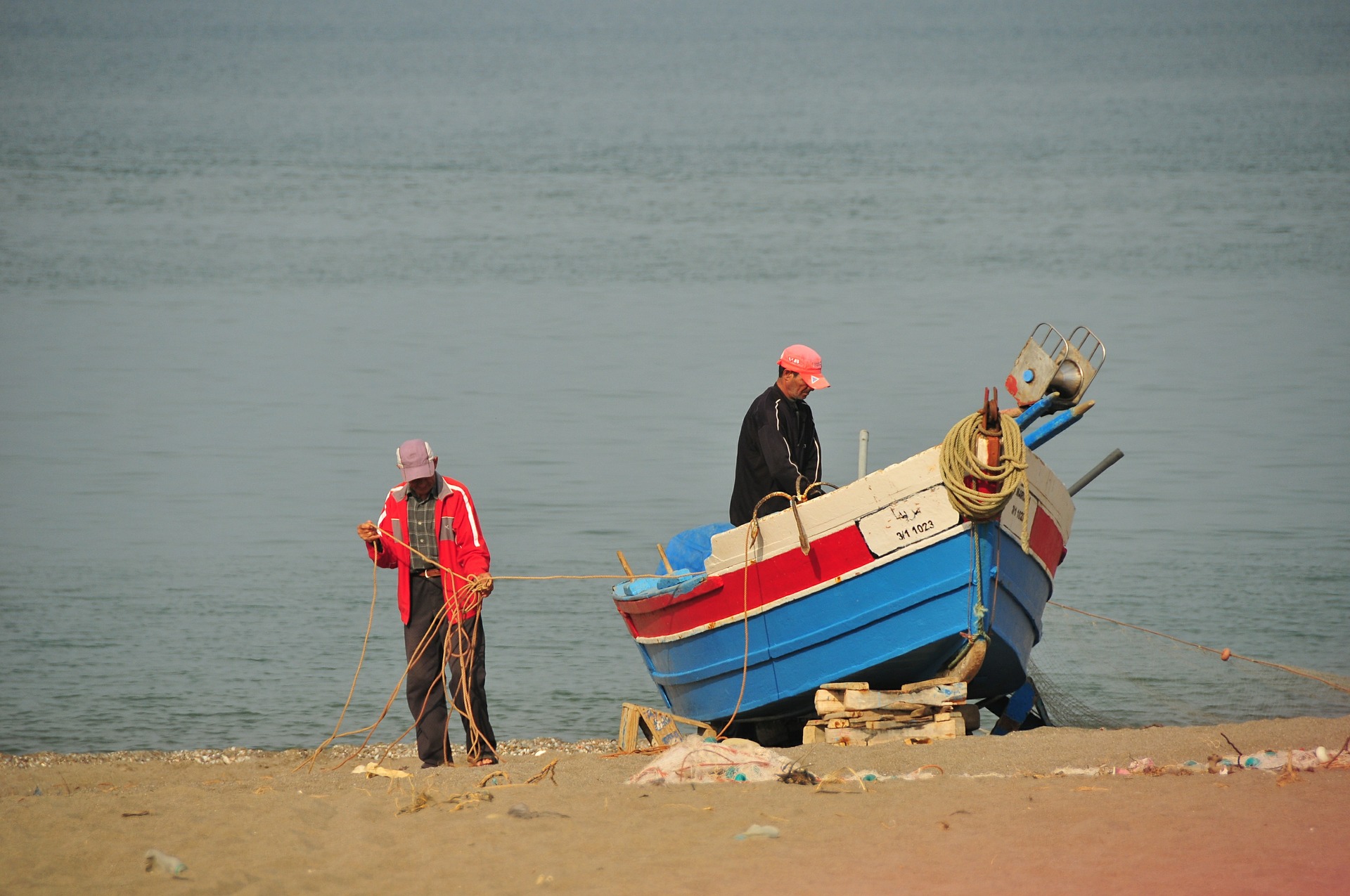 locals bij een visserboot op het strand in oualidia
