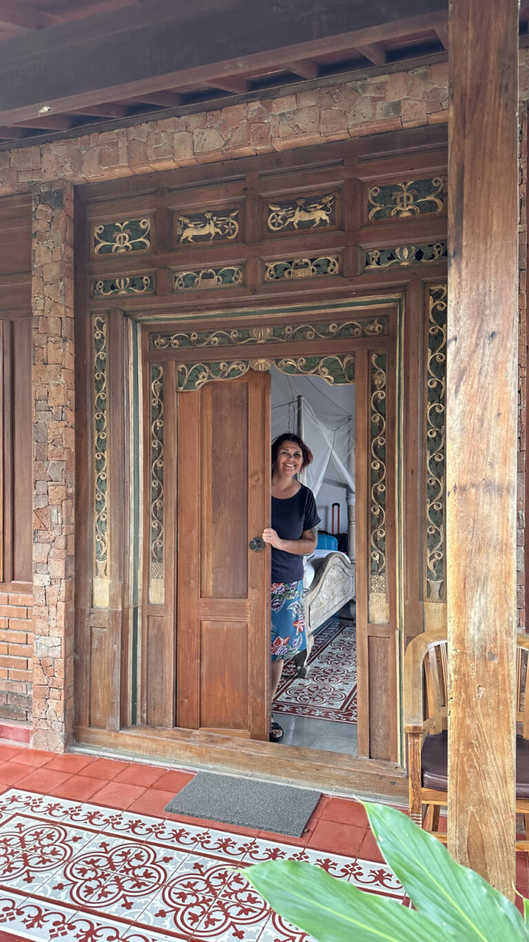 vrouw staat achter gedecoreerde deur van traditioneel huis op indonesie