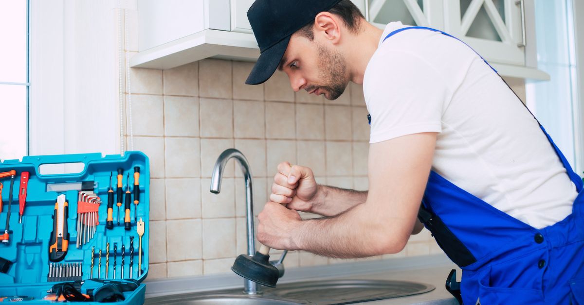 Professional plumber performing emergency drain service in a kitchen.
