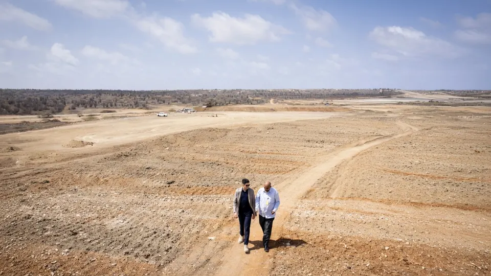 Twee mensen lopen door een droog en kaal landschap