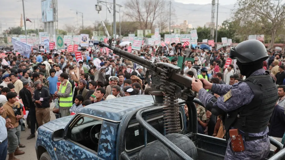 Een gewapende Houthi-strijder rijdt tijdens een bijeenkomst door een menigte in Jemen