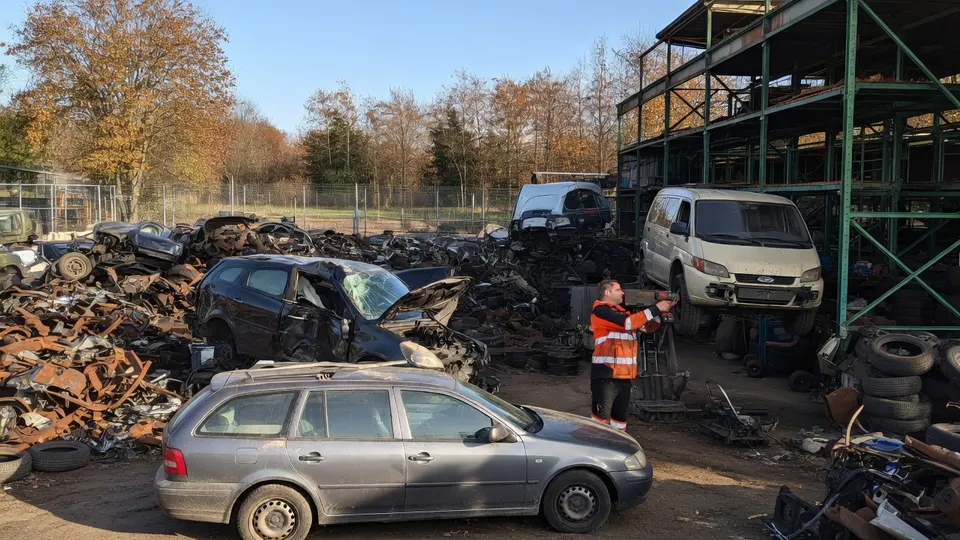 Medewerker tussen beschadigde auto's op het terrein van een autosloperij in Udenhout