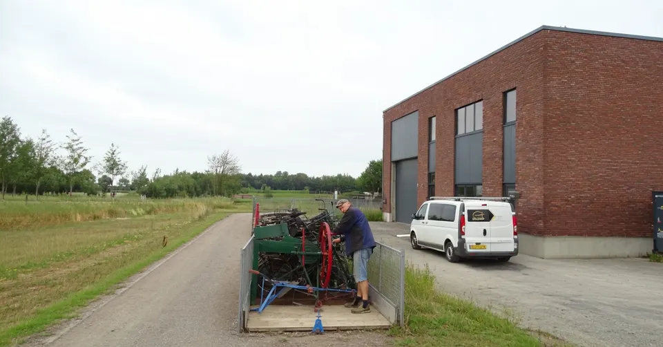 Vrijwilliger verplaatst historische landbouwwerktuigen bij aannemersbedrijf Van de Kolk in Oostendorp