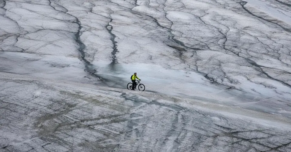 Een fietser rijdt over de smeltende Zwitserse gletsjer