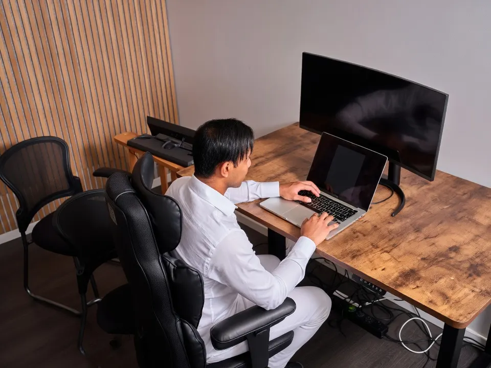 Een medewerker werkt achter meerdere schermen aan een bureau