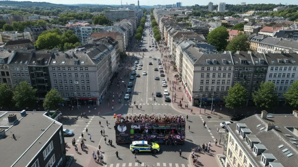 De Pride-optocht in Hamburg trekt door de straten, met een wagen en politiebegeleiding