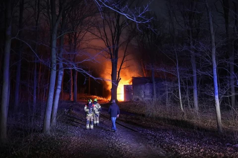 Brandweer loopt richting een loods die in Geffen in brand staat