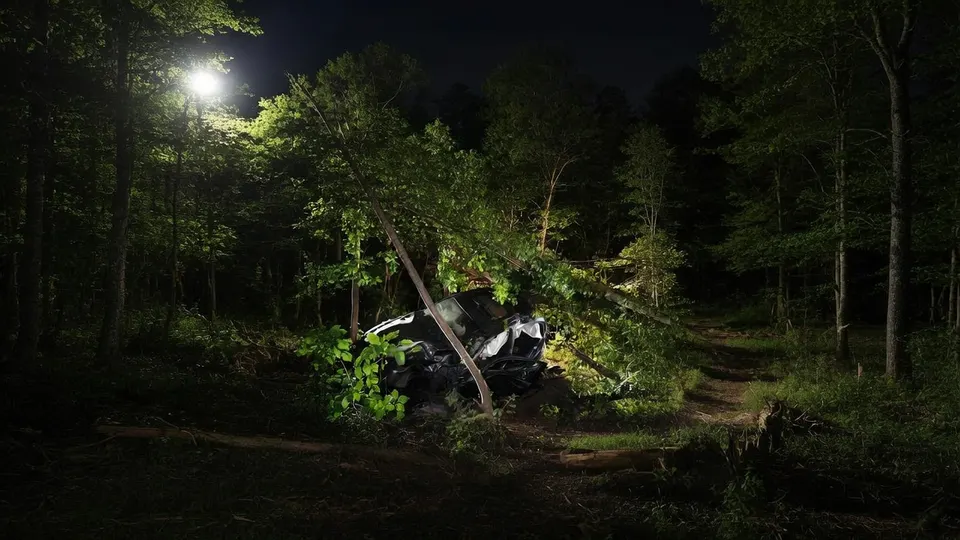 Hulpdiensten onderzoeken de zwaar beschadigde auto in het bosperceel langs de Eerdsebaan bij Veghel