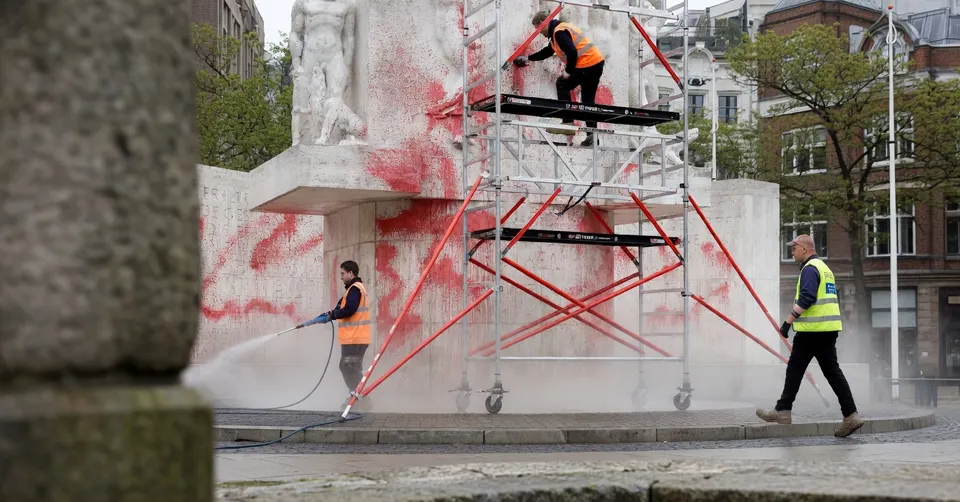 Schoonmakers verwijderen graffiti van het bekladde Nationaal Monument op de Dam in Amsterdam