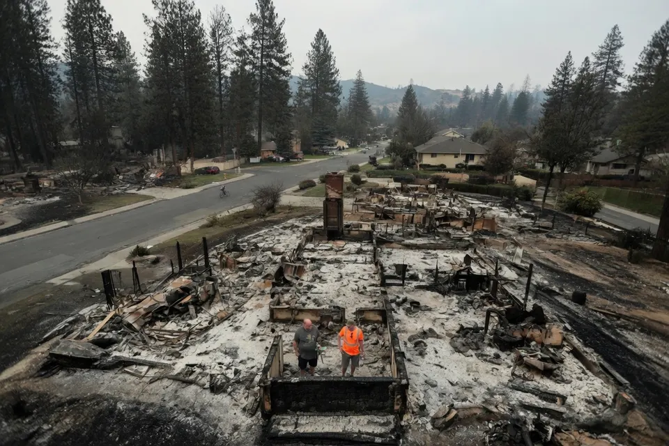Hulpverleners bekijken de resten van een door natuurbranden verwoest huis in Spokane County