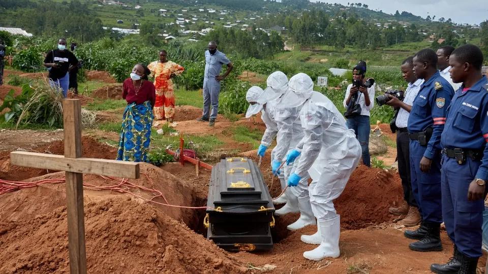 Hulpverleners in beschermende pakken plaatsen een kist in een graf in Congo