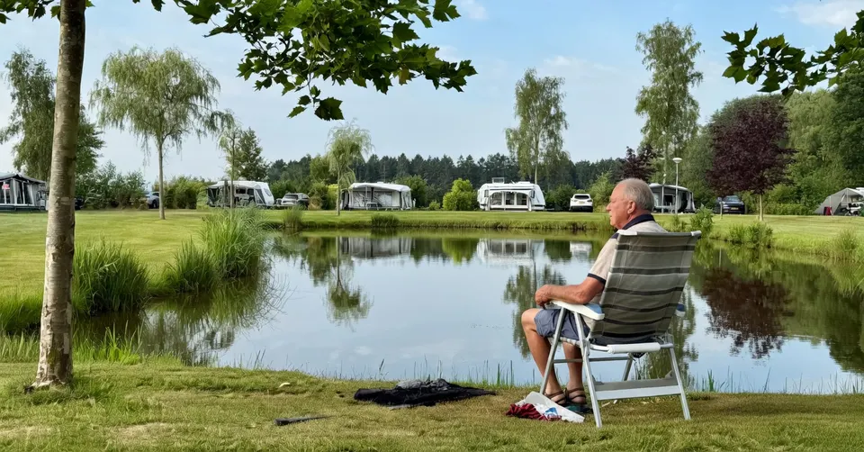 Gast kijkt uit over de vijver op een camping voor volwassenen in Groningen