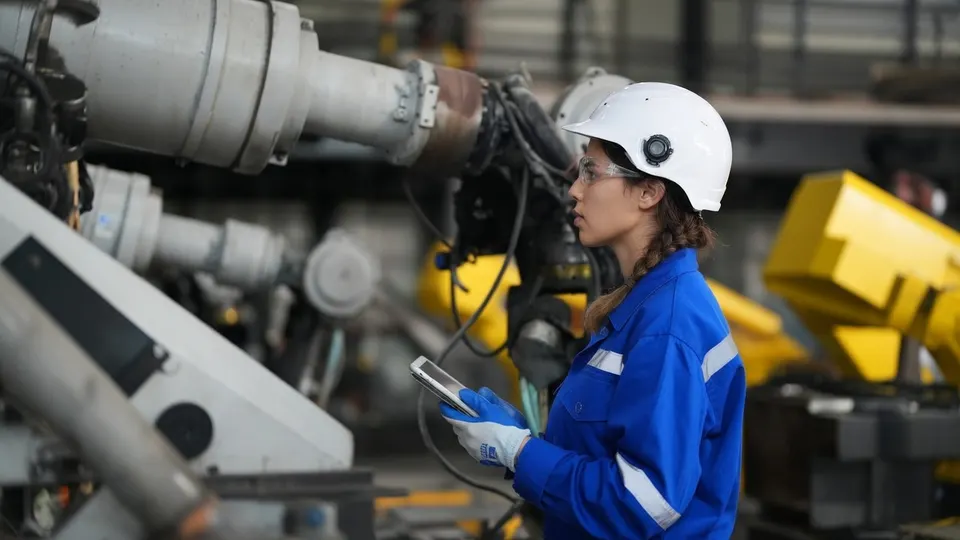 Medewerker van Reimagine Robotics met tablet tussen industriële robots