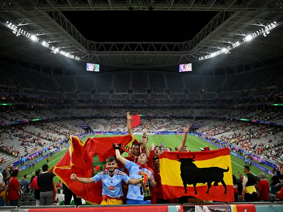Spaanse en Marokkaanse voetbalfans tonen vlaggen in een stadion