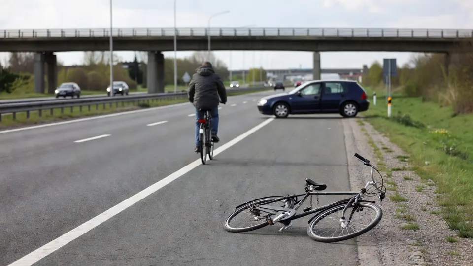 Fietser rijdt over de snelweg bij Utrecht, terwijl een fiets op de vluchtstrook ligt