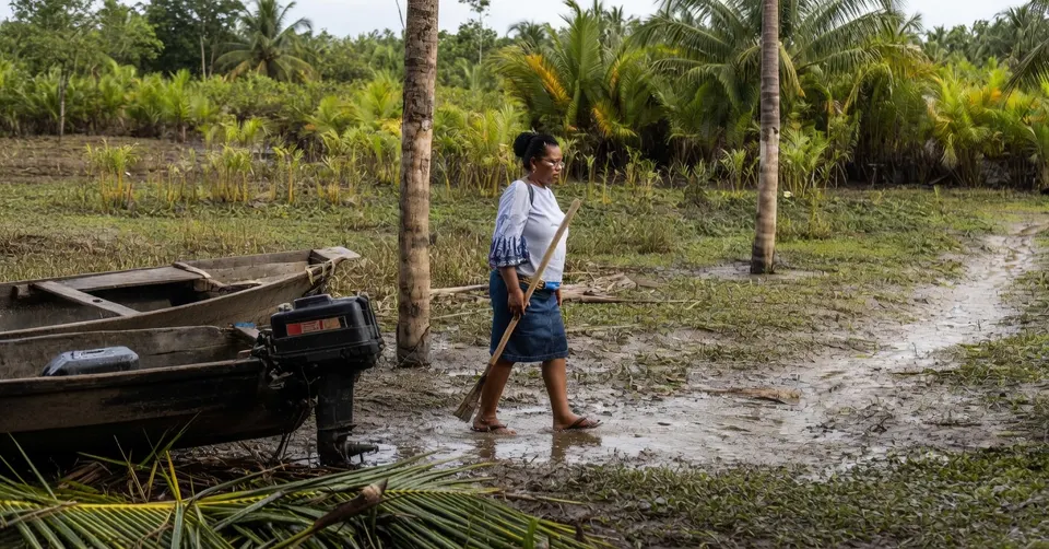 Vrouw loopt langs een boot in de vervuilde Nigerdelta in Nigeria