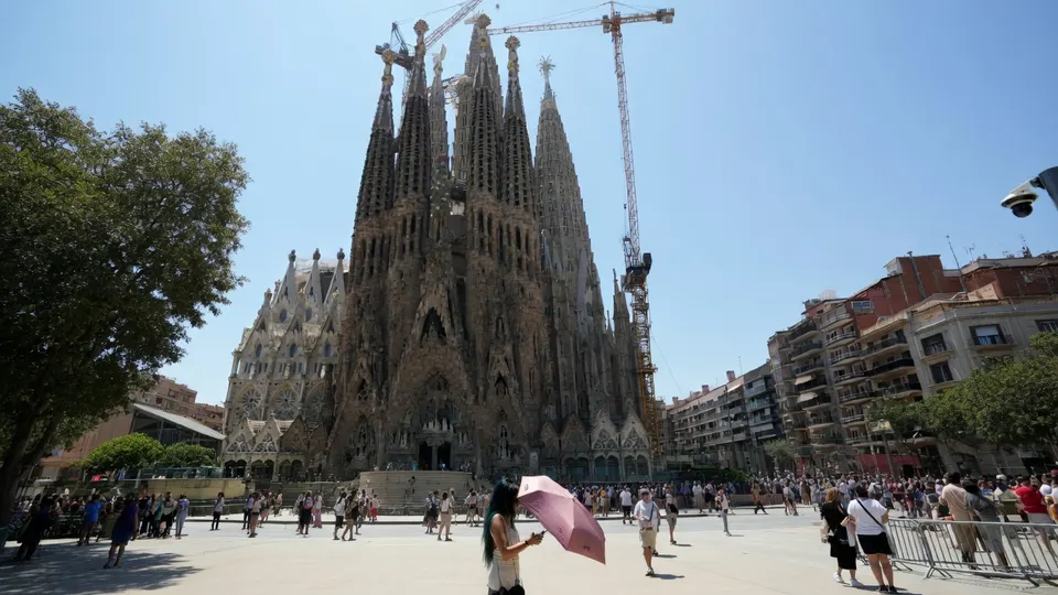 Toeristen bezoeken de Sagrada Família in Barcelona tijdens een hete zomerdag