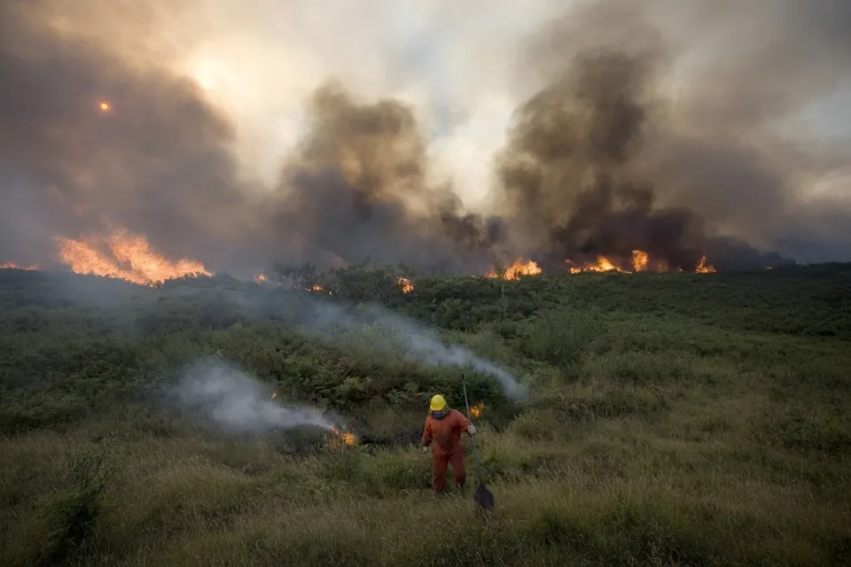 Een brandweerman bestrijdt een natuurbrand in droog grasland in Spanje