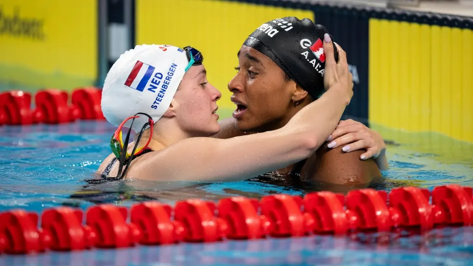 Sara Curtis en Marrit Steenbergen omhelzen elkaar na de halve finale van de 50 meter rugslag