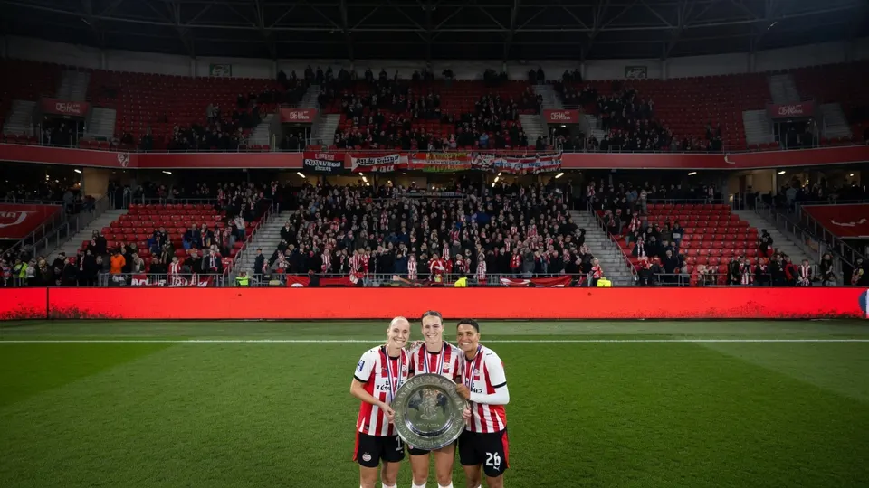 Drie speelsters van FC Utrecht poseren met de kampioensschaal in het stadion