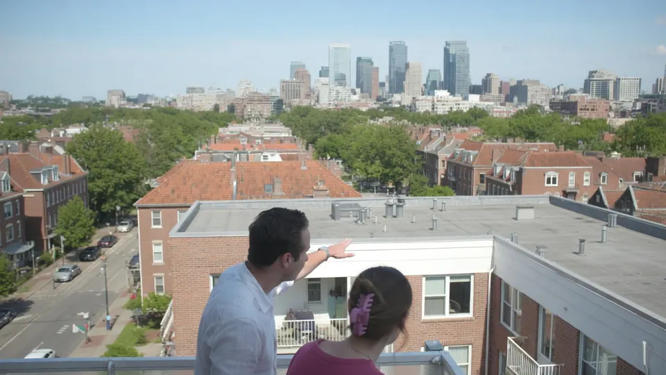 Twee mensen bekijken vanaf een balkon woningen in een stad