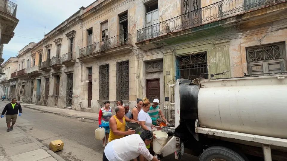 Cubanen halen water uit een tankwagen in een straat in Cuba