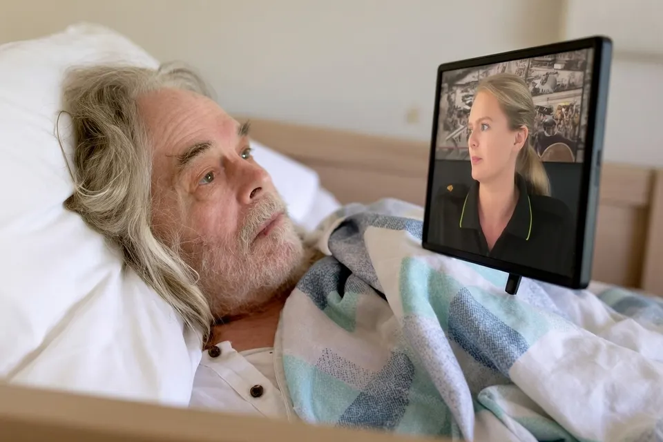 Patiënt ‘Lucky’ ligt in het OLVG en krijgt via een beeldscherm uitleg van een zorgverlener