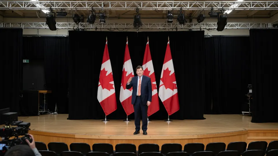 Premier Mark Carney tussen Canadese vlaggen tijdens een persconferentie
