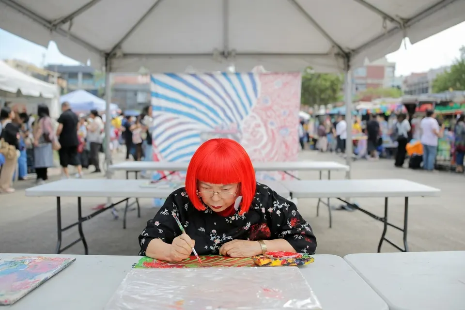 Yayoi Kusama schildert tijdens een kunstmanifestatie