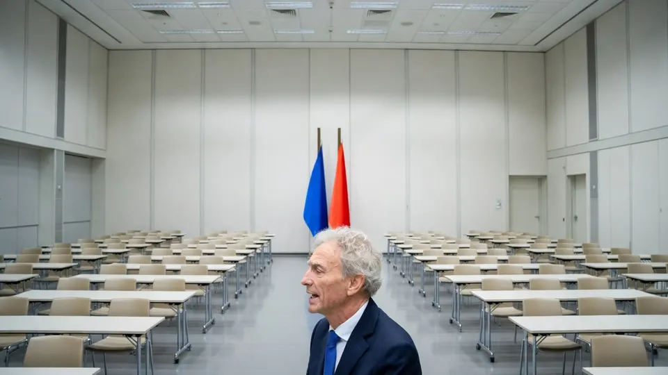 Paul Rosenmöller in een vergaderzaal met Nederlandse en Europese vlag
