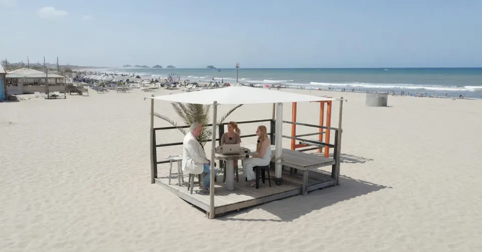 Drie mensen praten in een strandpaviljoen aan zee
