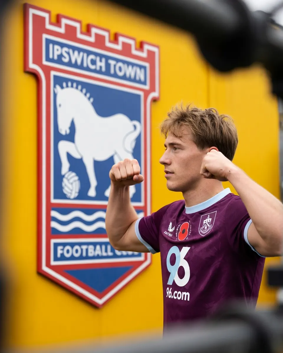 Zian Flemming poseert voor het logo van zijn nieuwe club Ipswich Town