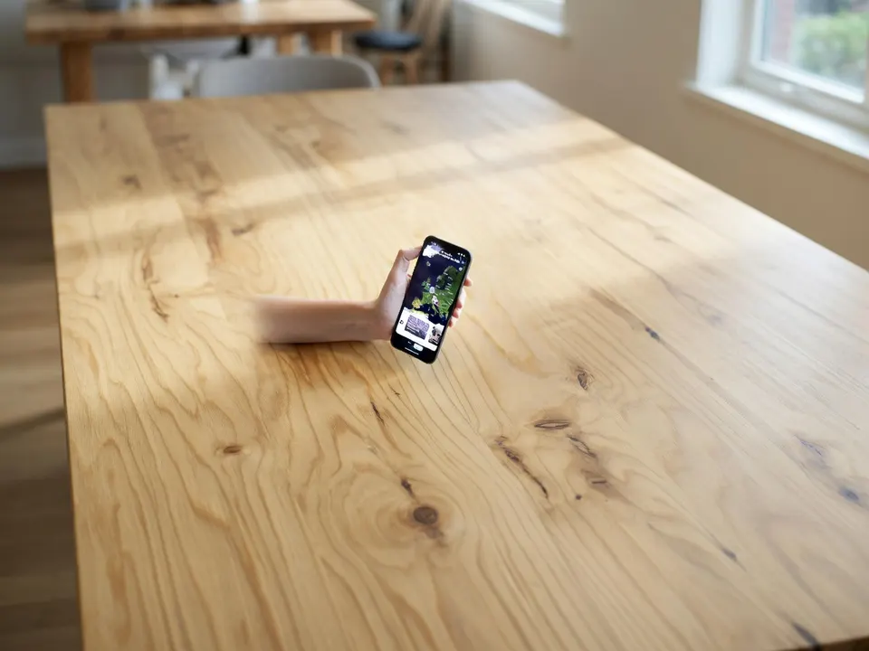 Een smartphone met de reisapp Polarsteps op een houten tafel
