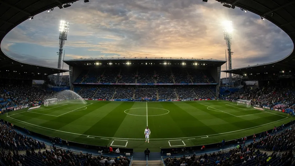 Een voetbalstadion met supporters en sproeiers op het veld