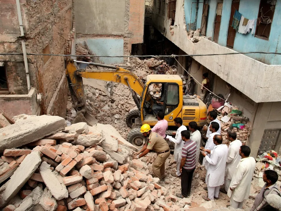 Reddingswerkers zoeken met een graafmachine naar overlevenden in het puin van een ingestort studentencomplex in Delhi