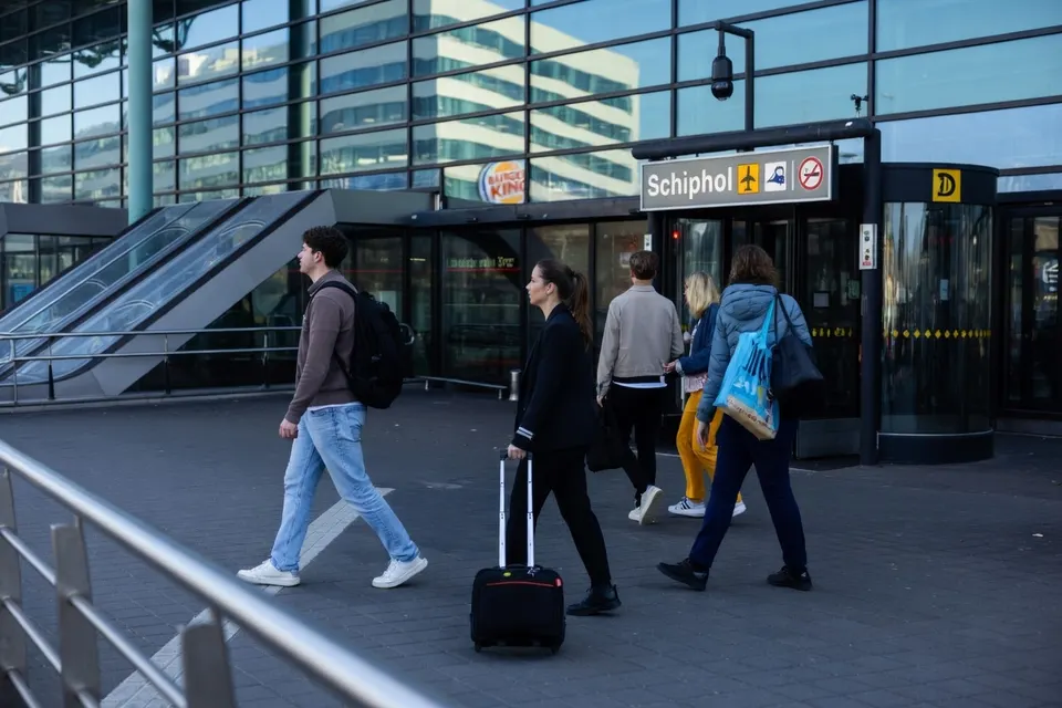 Reizigers lopen langs de ingang van Schiphol
