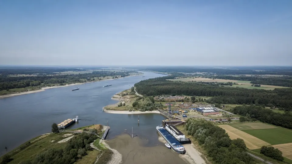 Binnenvaartschepen varen over een rivier tijdens droogte